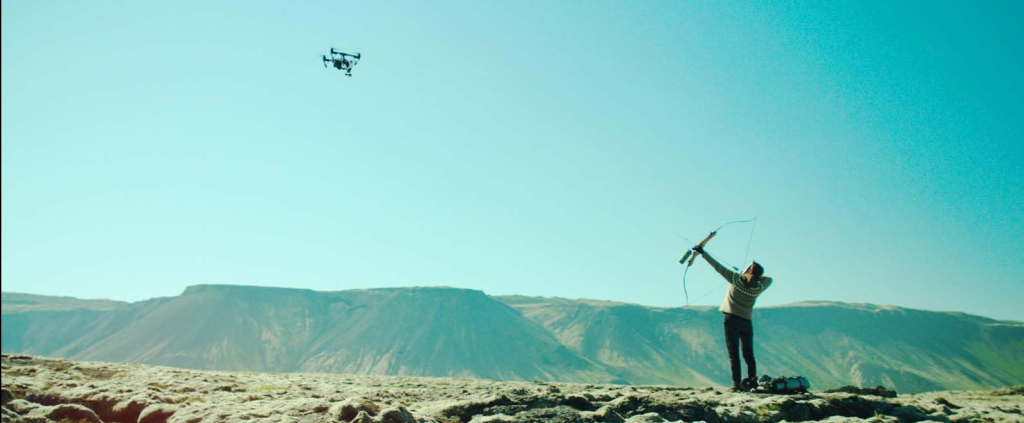 a still from the movie, showing the protagonist shooting a drone with bow and arrow.
